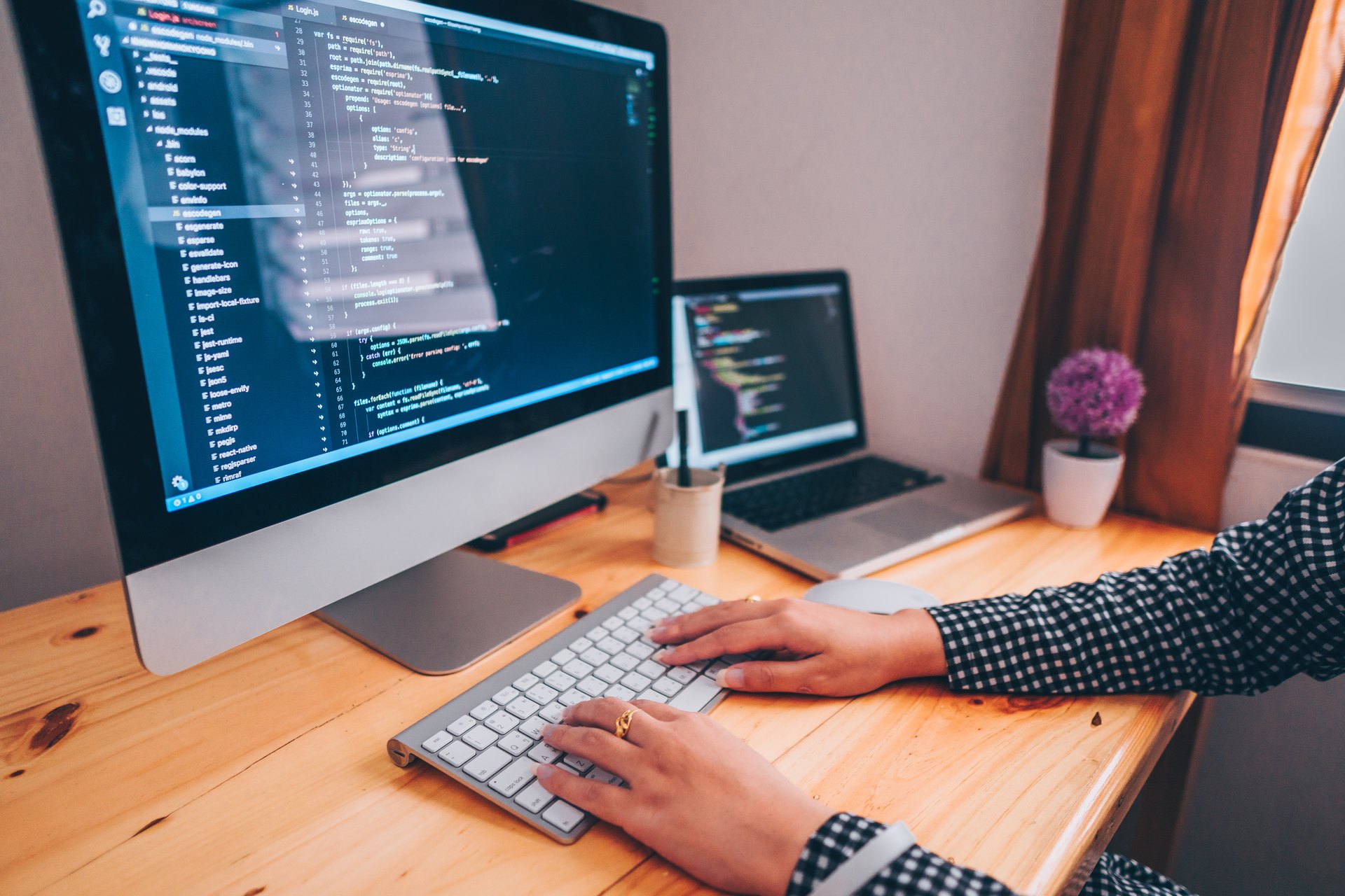 Person typing at a desk with two computer screens