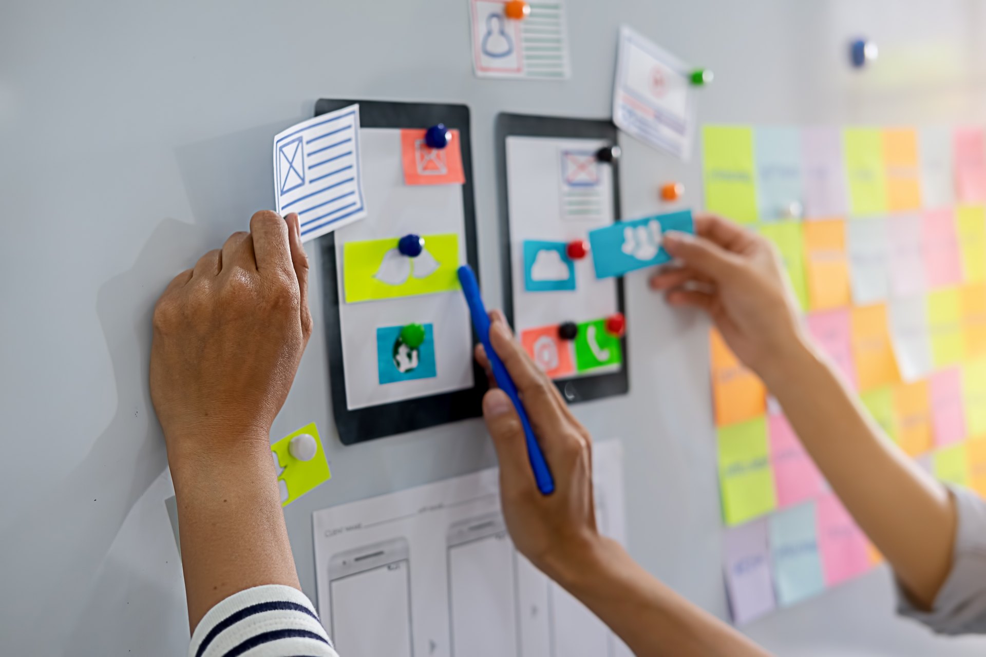 People arranging interface sketches and planning notes