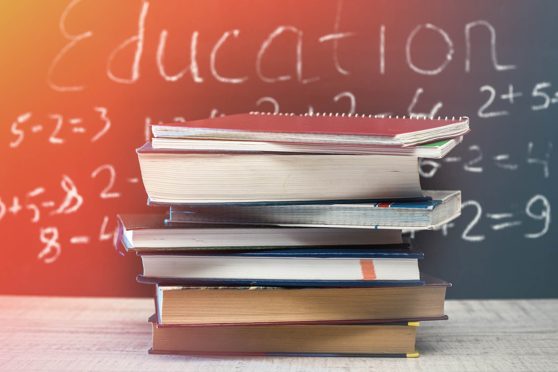 Stack of books in front of an education chalkboard