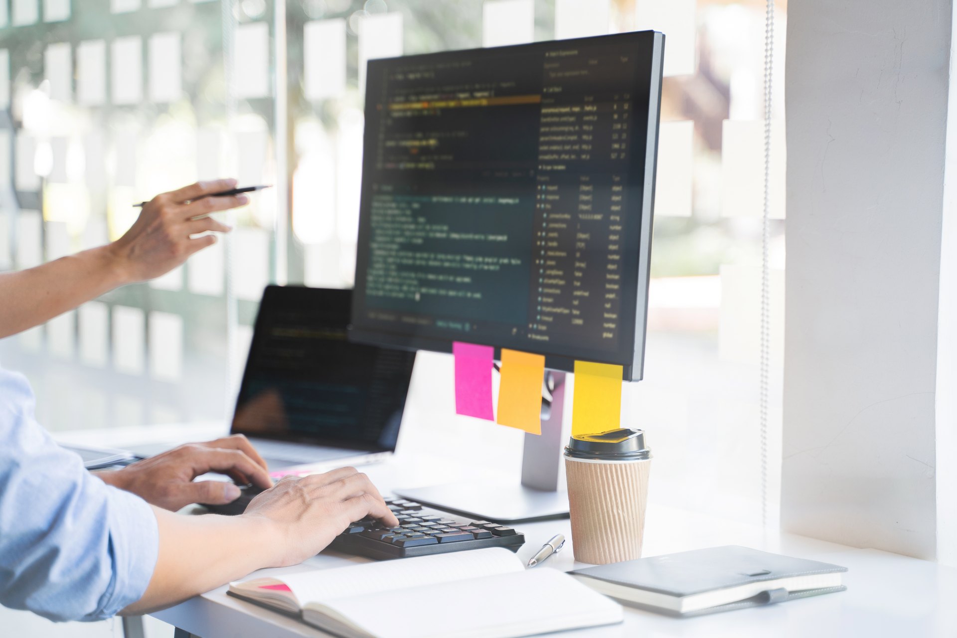 Developer working with code on a desktop monitor