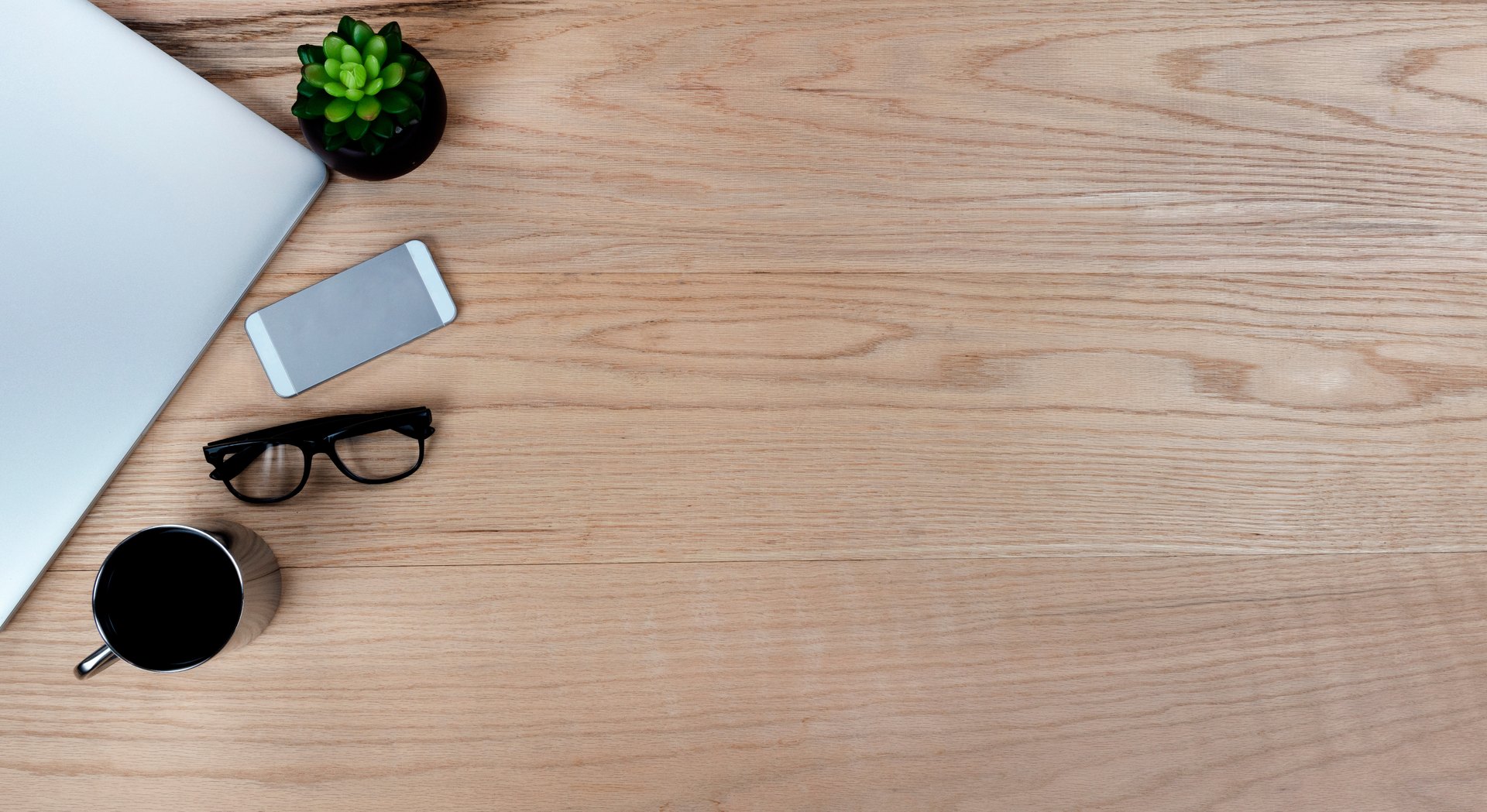 Wooden desk with a laptop, notebook, coffee and glasses