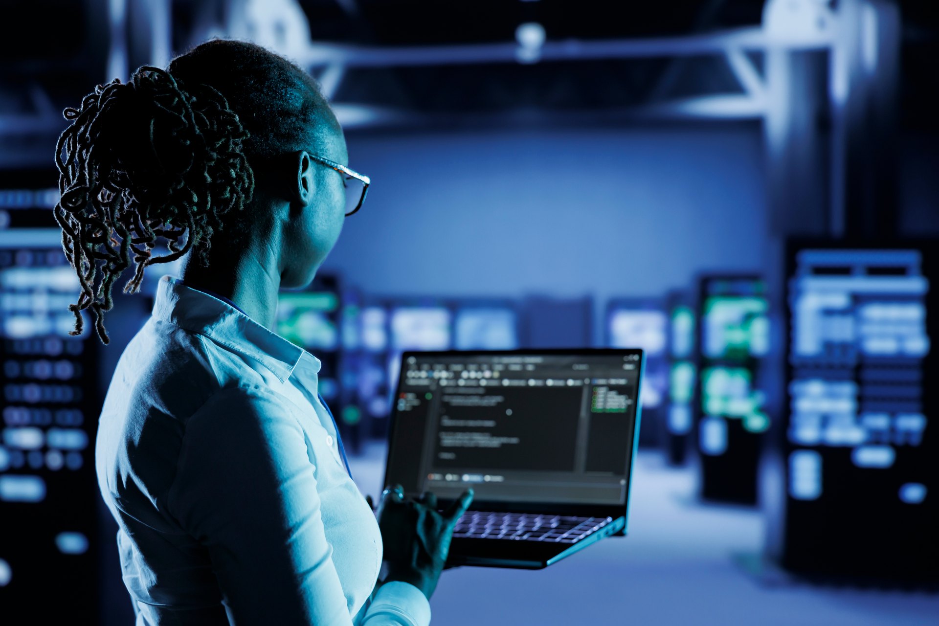 Technical worker using a laptop among equipment racks